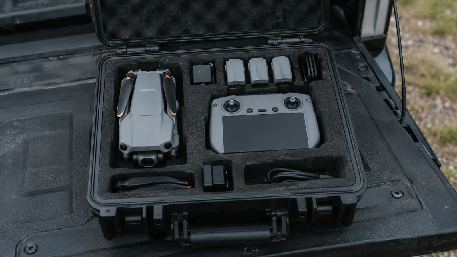 Open hard-shell drone case on a tailgate with the drone, controller, and accessories packed inside